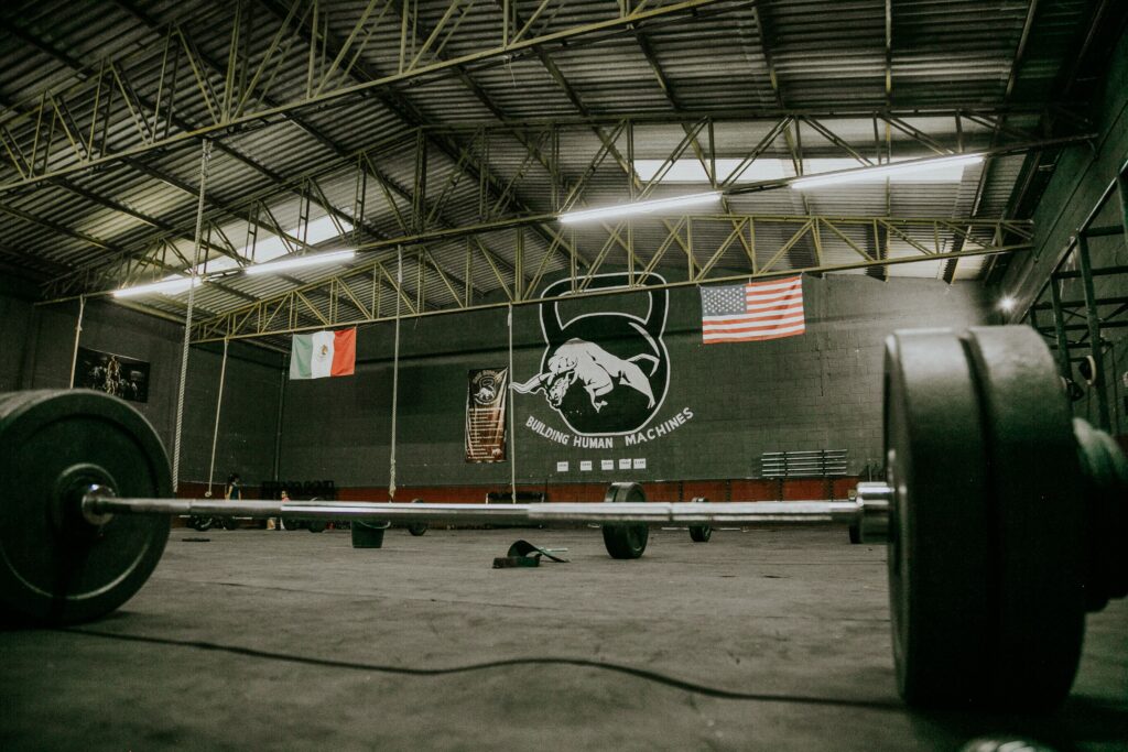 Large industrial gym interior with barbells, Mexican and American flags, and gym equipment.